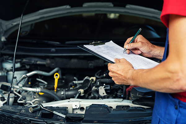car maintenance and repair - mechanic writing checklist paper on